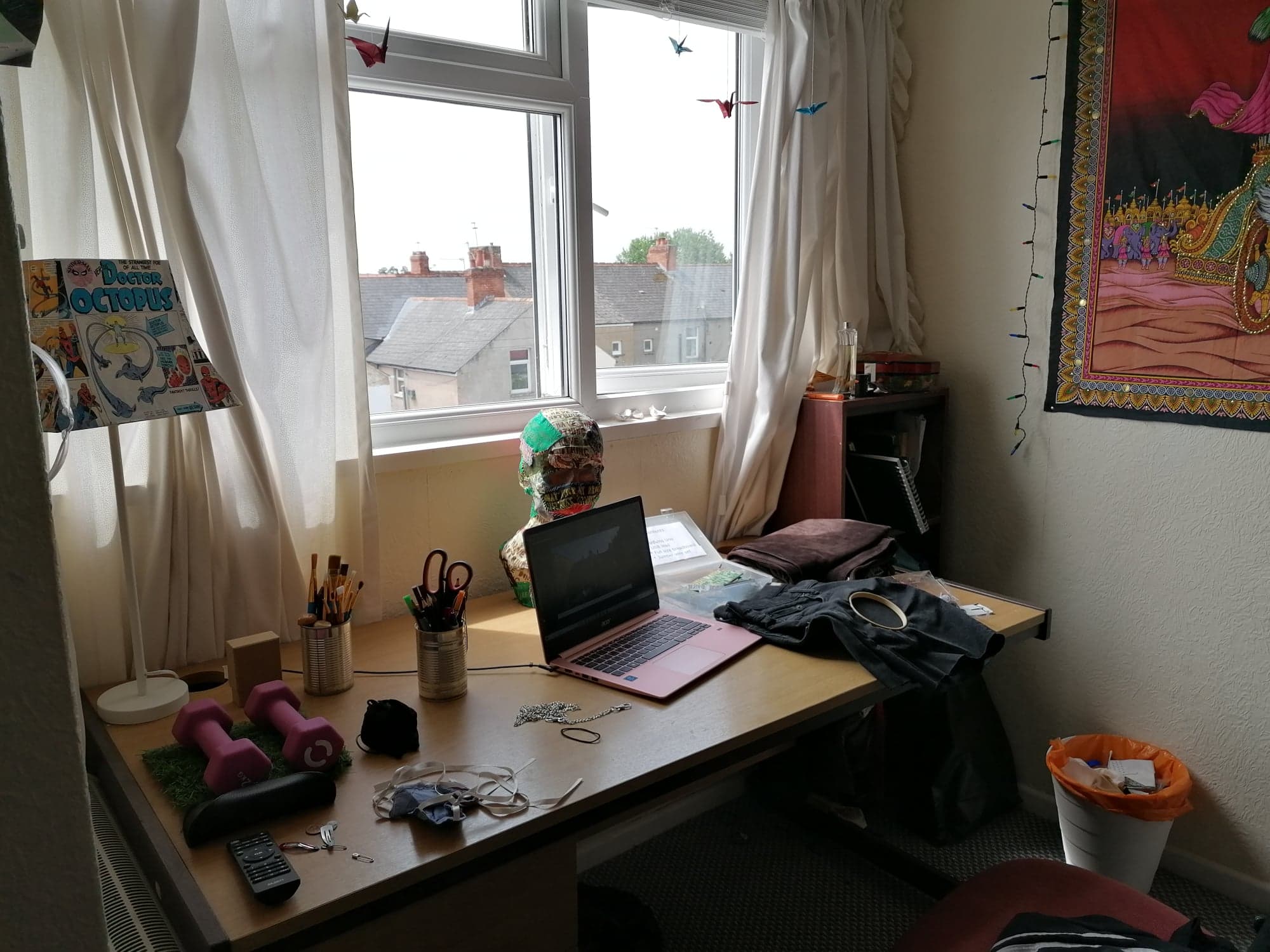 An image of Martha's workspace. A desk in front of a window. A laptop and embroidery tools are on the desk.